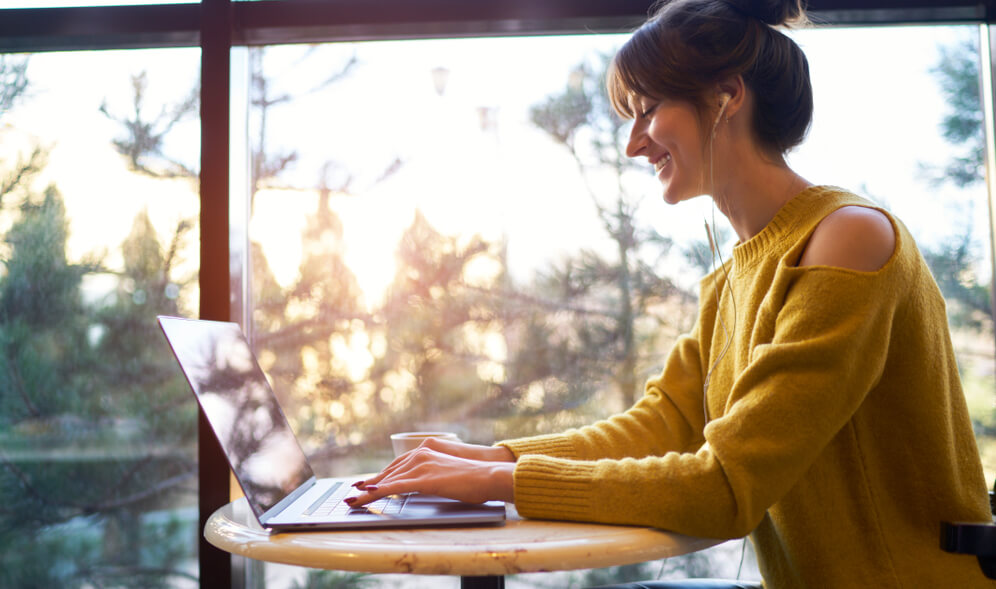 shows woman writing blog article on her laptop